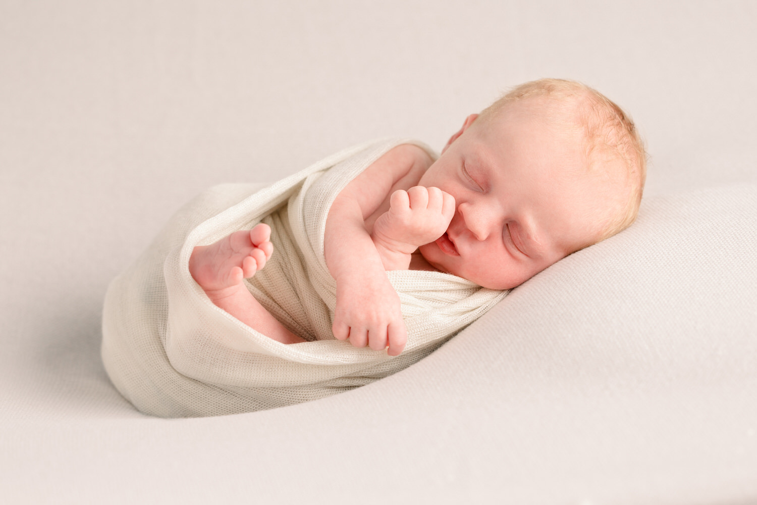 newborn baby posing on a blanket as the baby is being photographed professionally in studio