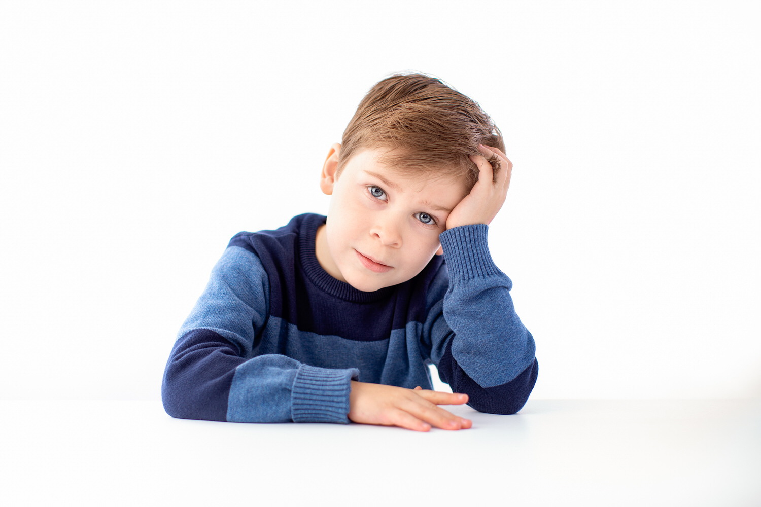 a young boy thinking as he looks directly into the camera during a portrait studio photo shoot
