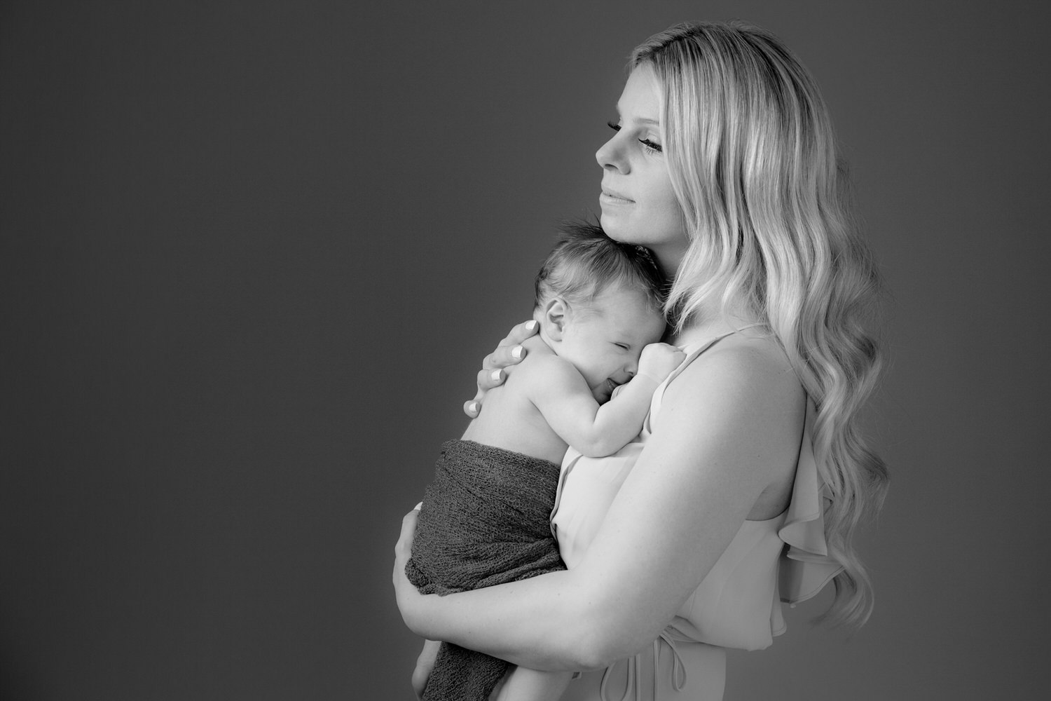 Mom holding her newborn baby during her photography studio shoot in Calgary