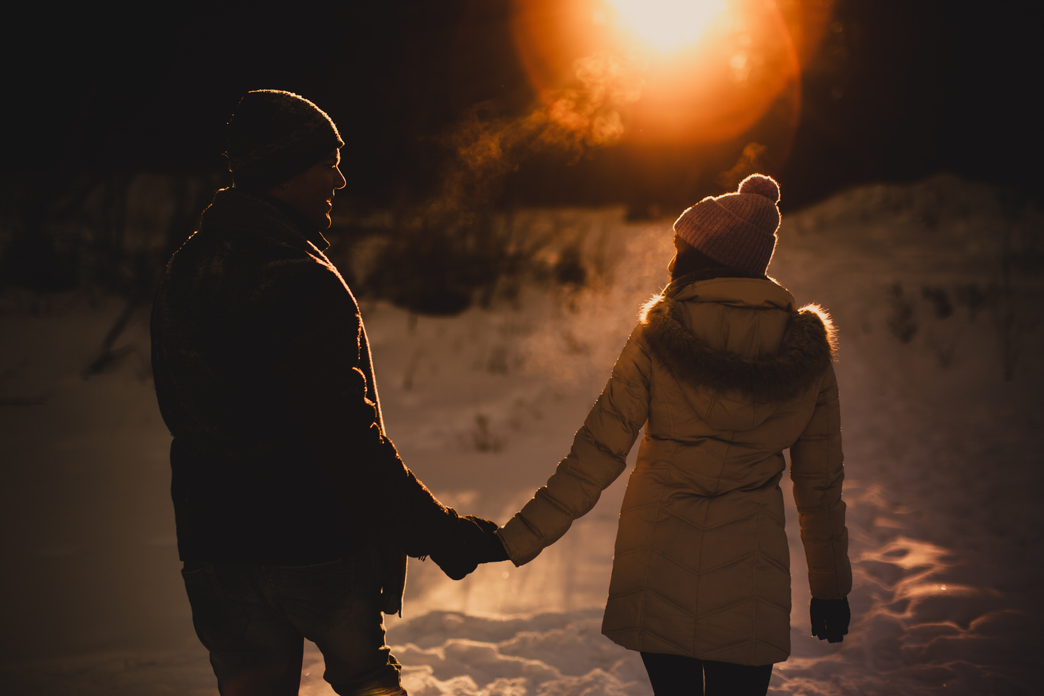 An engaged couple holding hands in Calgary during sunset in the winter